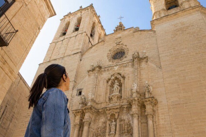 Una mujer parada frente a un edificio grande y antiguo con una alta torre de campanas. 2