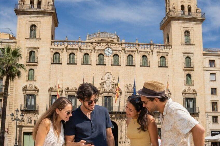 Un grupo de personas frente a un edificio histórico con una torre de reloj. 4