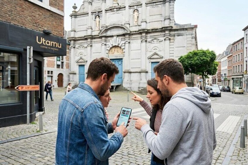 Un groupe de personnes utilisant une tablette, un bâtiment avec une horloge et un panneau indiquant « Saint-Lambert ». 1