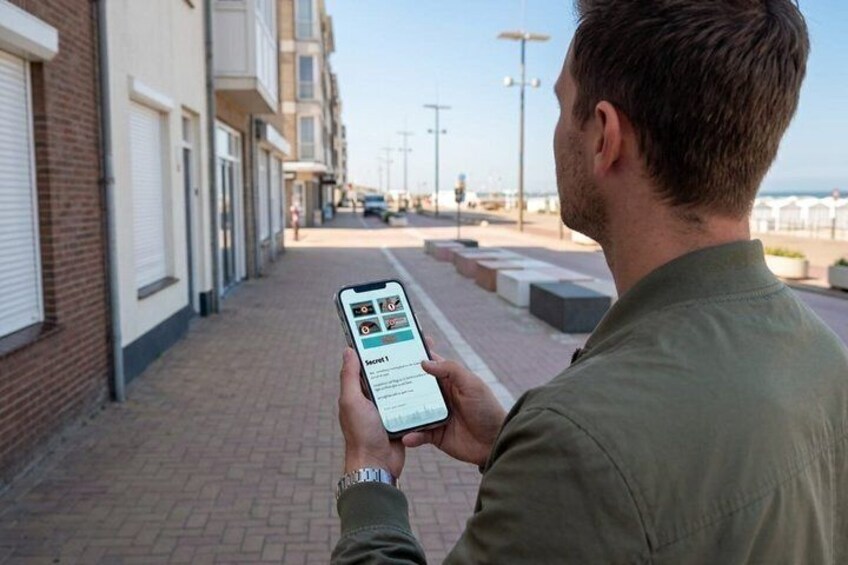 A person holding a smartphone with a map application, walking on a brick-paved sidewalk. 4