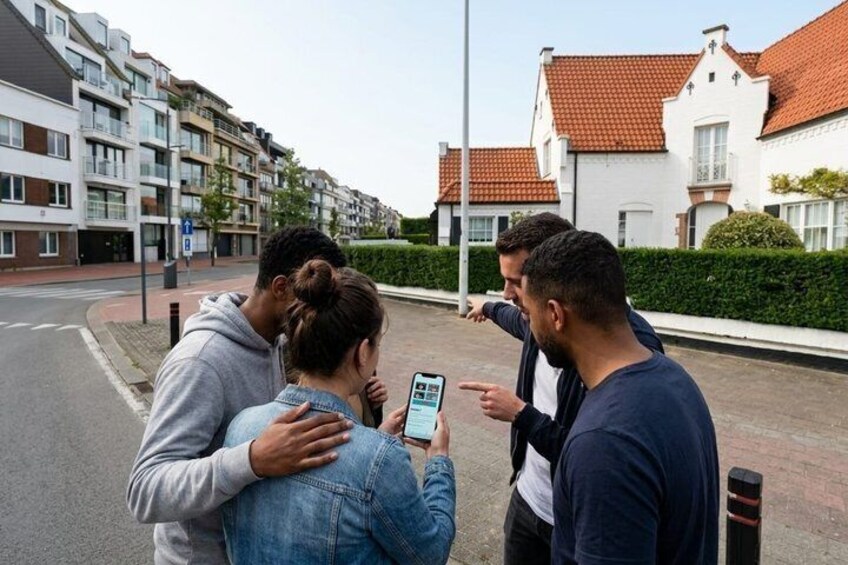 A group of people standing on a sidewalk, looking at a smartphone. 3