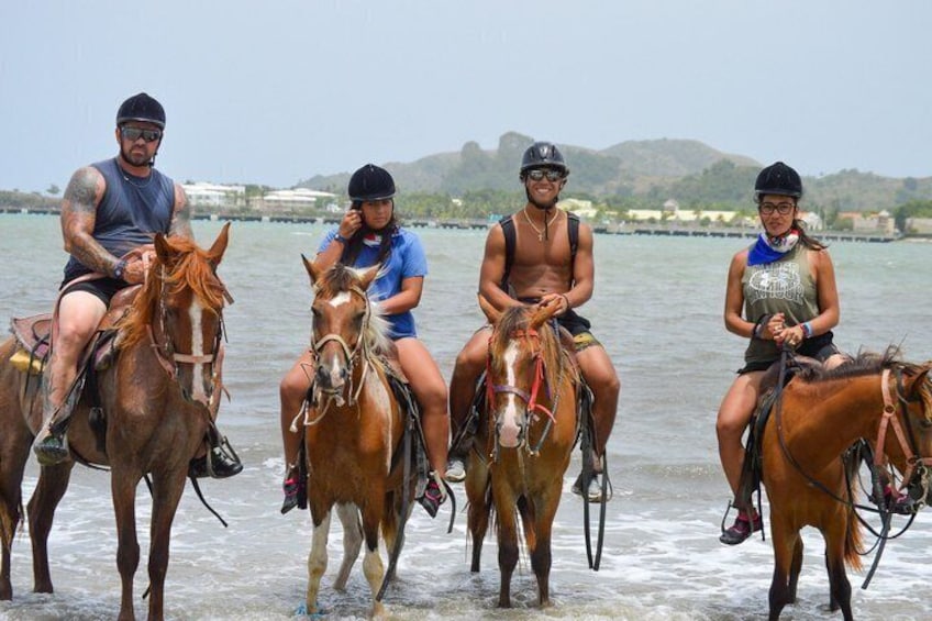 Quatre personnes à cheval, se promenant le long du bord de l’eau. 4