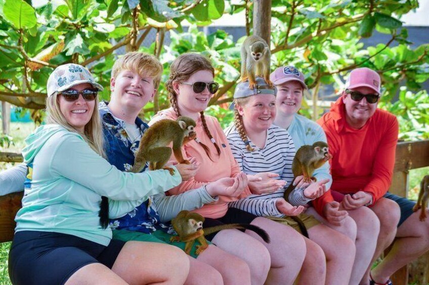 Un groupe de personnes assises sur un banc, avec de petits singes sur leurs genoux. 5