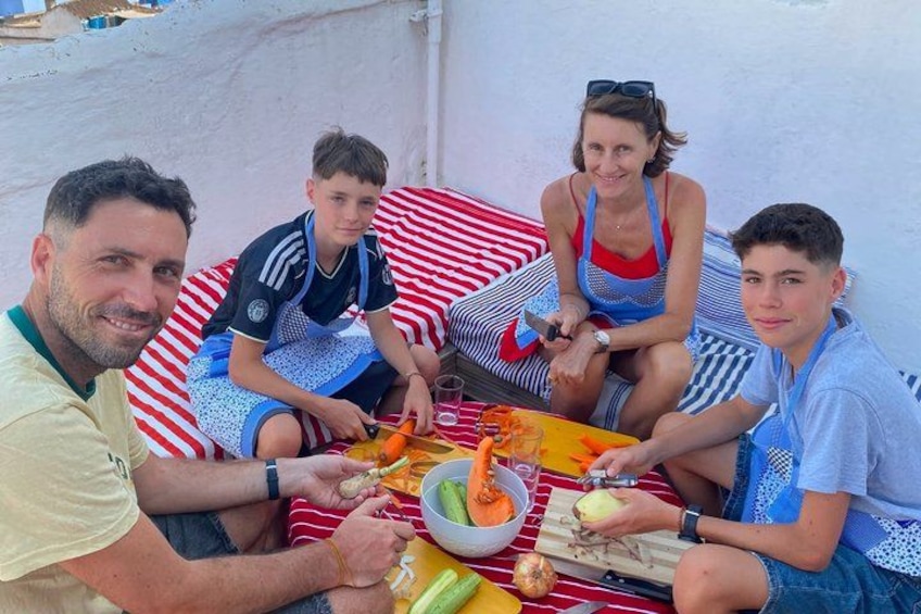 A family dining outdoors with a table set for a meal, including vegetables and a bowl of salad. 1