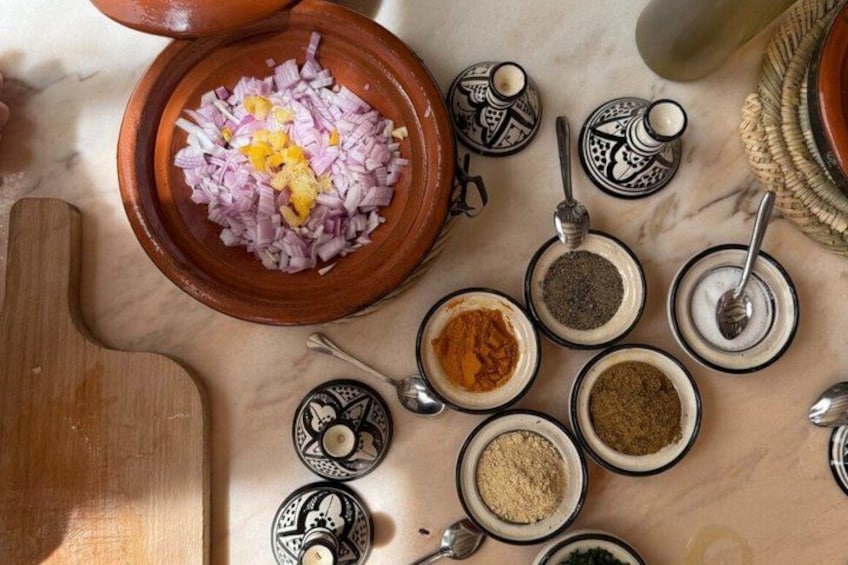 A variety of spices and ingredients on a marble surface, including chopped onions, turmeric, and other seasonings. 3