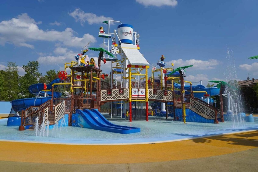 A water park with a blue slide, a water fountain, and a LEGO-themed play structure. 2