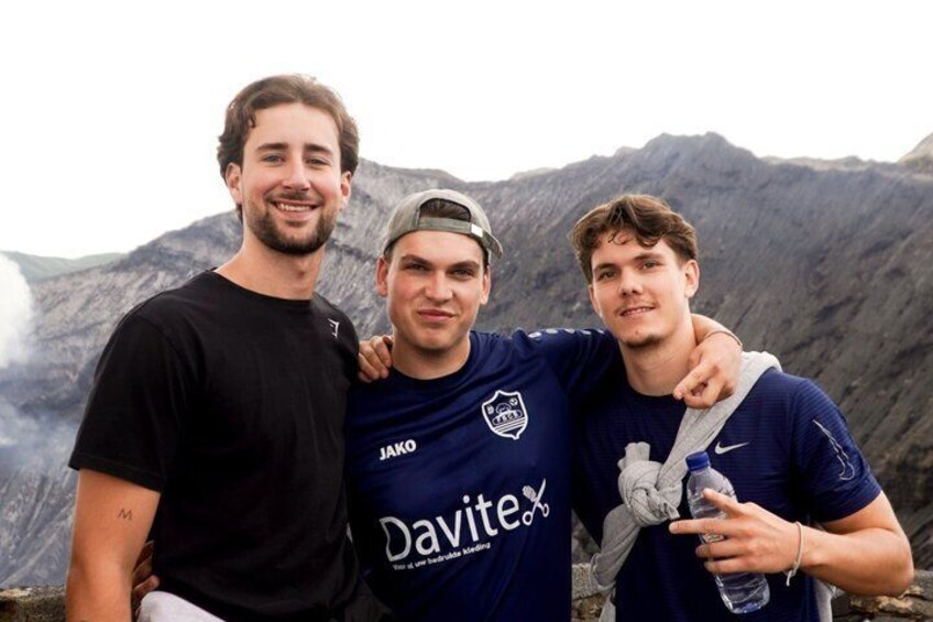 Three people standing outdoors with a mountainous landscape in the background. 3