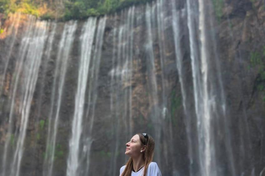 A waterfall with a person standing in front of it. 2
