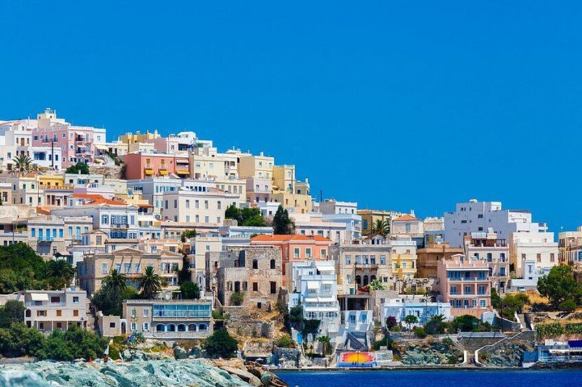A coastal town with colorful buildings, a clear blue sky, and a rocky shoreline. 2