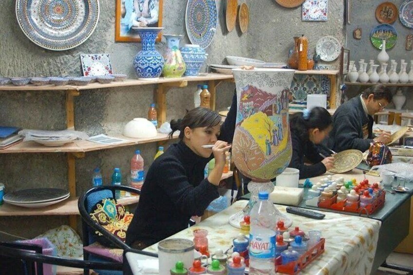 A pottery workshop with shelves of colorful plates and a large vase with a painted design. 2