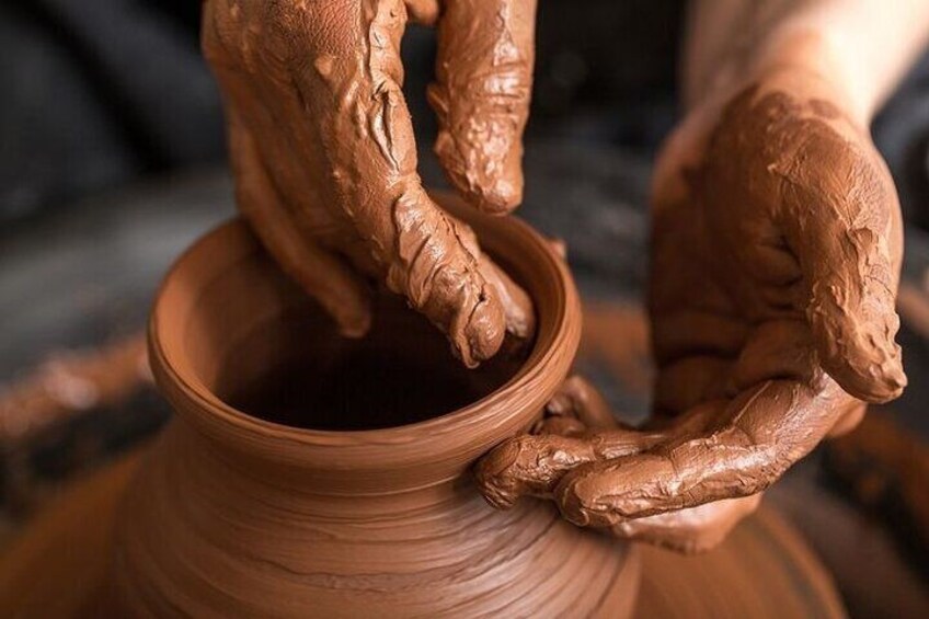 Hands shaping a clay pot on a pottery wheel. 3