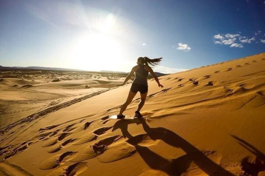 A person running on a sandy dune with footprints, under a clear sky. 2