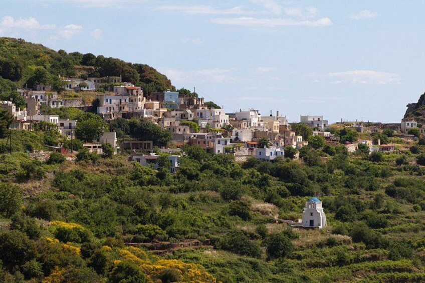 A hillside village with buildings, greenery, and a small white structure. 3