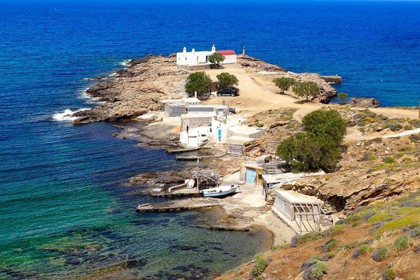 A coastal village with white buildings, a rocky shoreline, and clear blue sea. 2