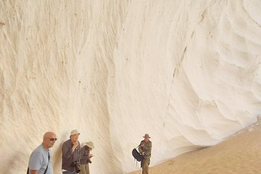 A large white rock formation with people standing at its base. 3