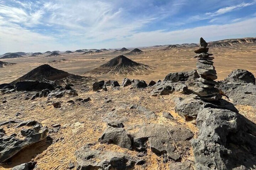 A rocky desert landscape with a prominent rock formation stacked vertically. 2