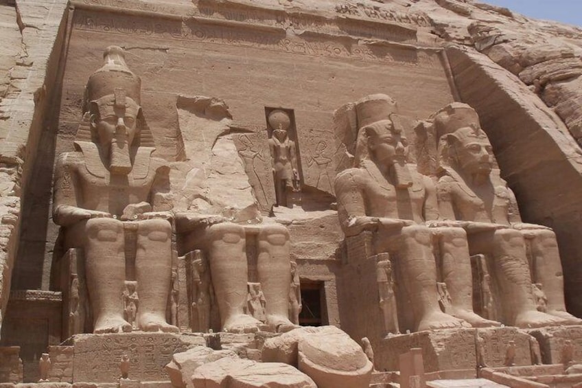 A large stone relief with figures of pharaohs and a central deity, carved into a cliff face. 4