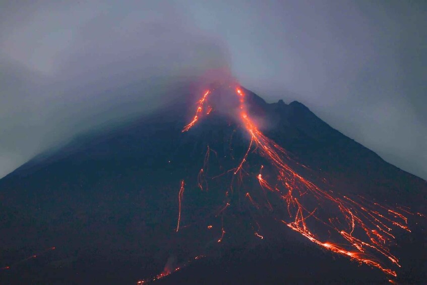 A volcano with lava flowing down its side at night. 3