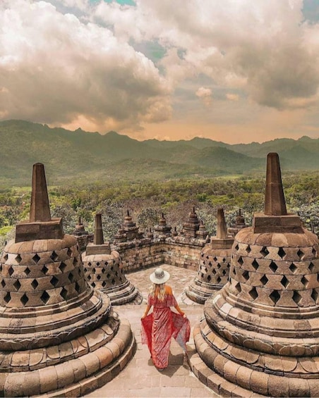 A person in a red dress walking towards a temple complex with tiered roofs. 5