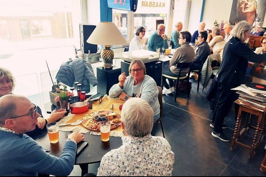 Un grupo de personas sentadas alrededor de una mesa en una cafetería, con una lámpara y diversos alimentos sobre la mesa. 4