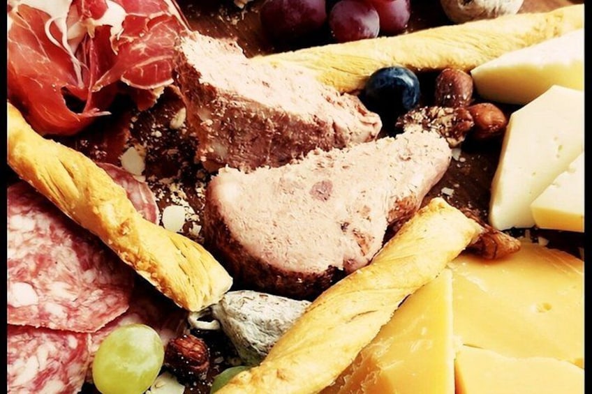 Una tabla de embutidos con diferentes carnes, quesos, frutas y frutos secos. 3