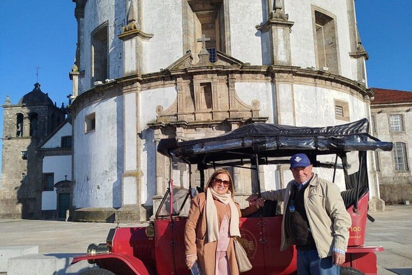 Un edificio histórico con un campanario, un vehículo rojo y dos personas. 4