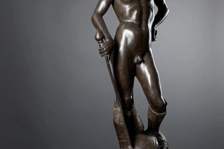 A bronze statue of a standing human figure with one hand on its hip and the other holding a staff. 5