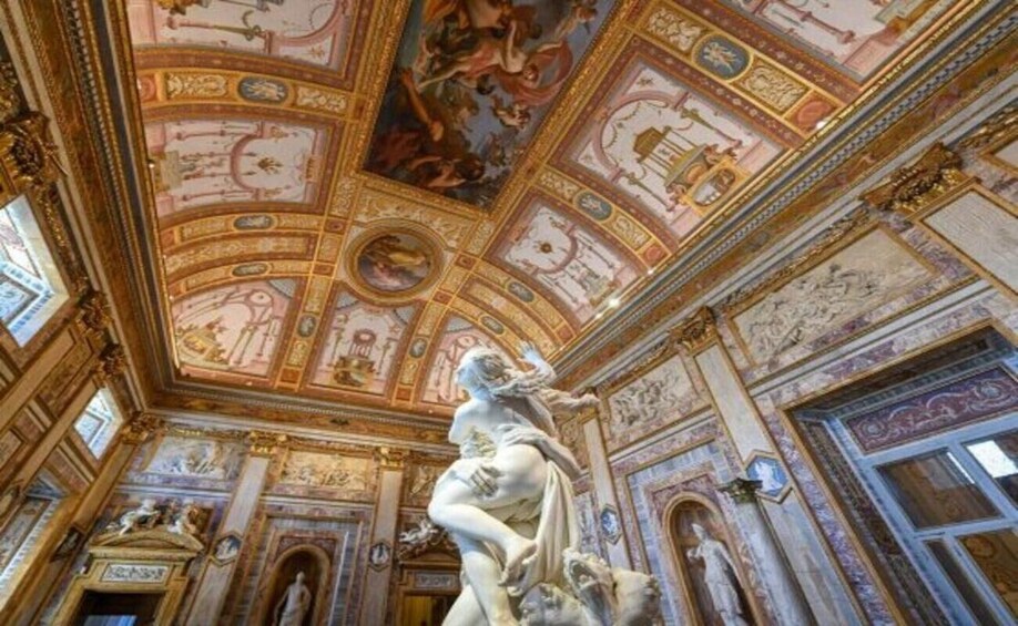 An ornate interior with a large frescoed ceiling, classical sculptures, and detailed wall decorations. 2
