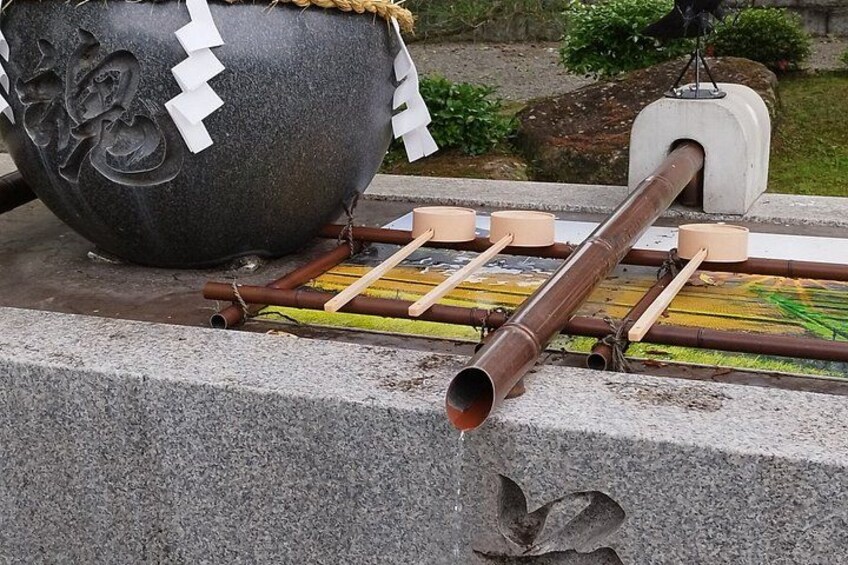 A traditional Japanese water wheel with wooden paddles, a stone basin, and a pipe. 1