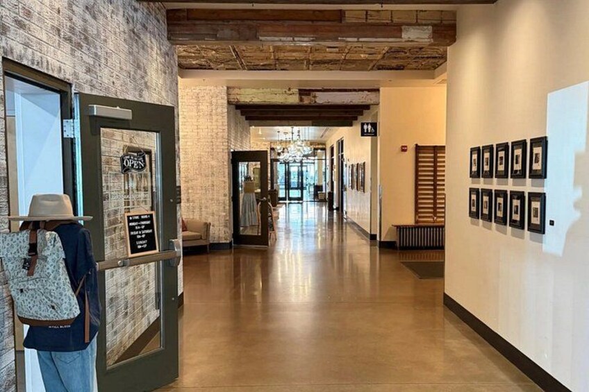 A hallway with a brick wall, a wooden ceiling, and framed pictures on the wall. 5