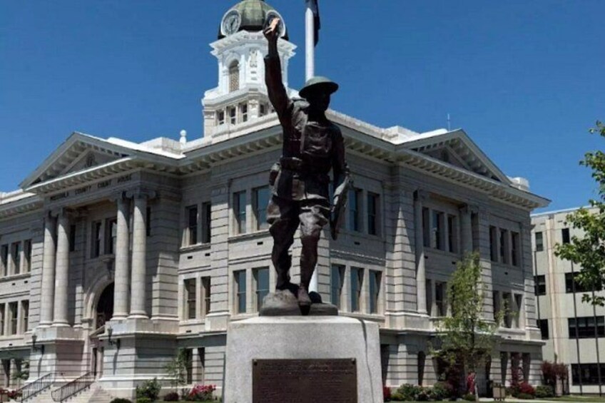 A statue of a person in uniform standing in front of a large building with columns and a dome. 4