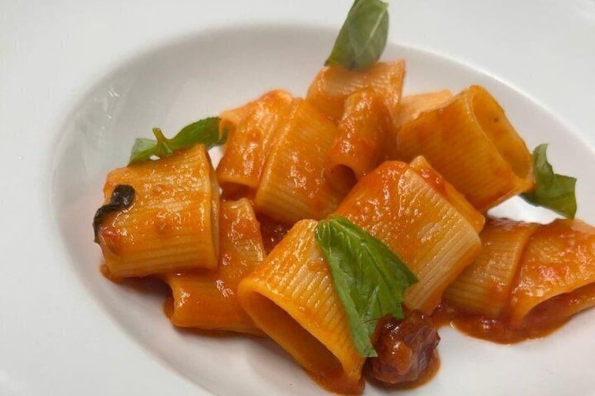 A plate of pasta with a tomato-based sauce and basil garnish. 2