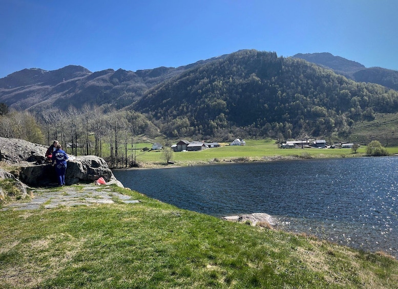 A lake with a rocky shoreline, a person near the water, and houses in the background. 4