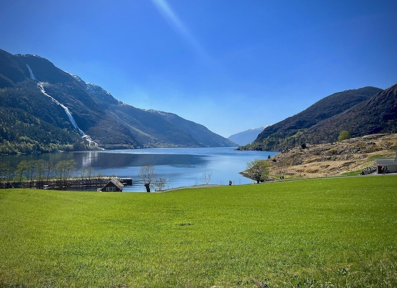 A serene lake surrounded by mountains, a clear sky, and a grassy foreground. 3