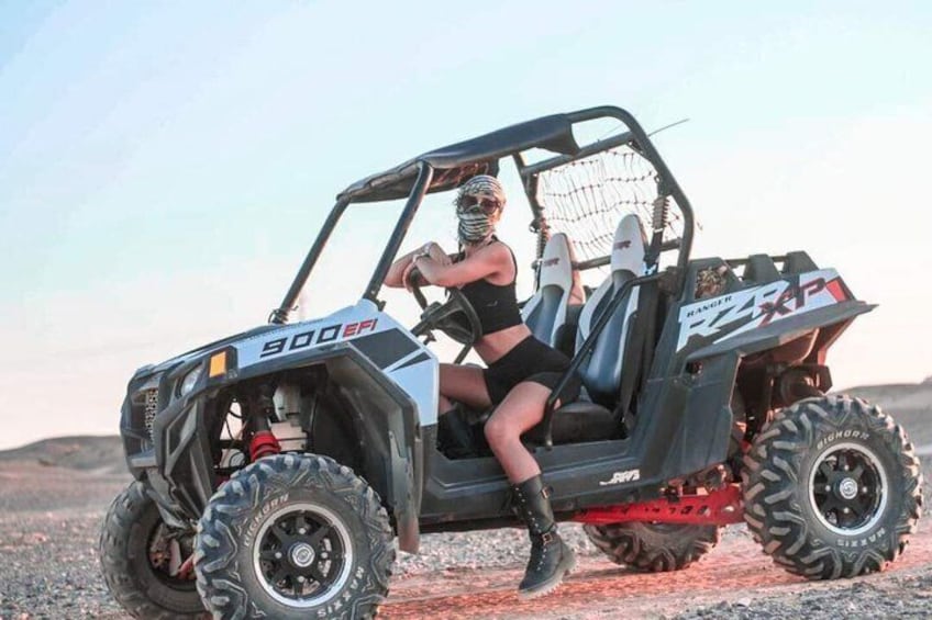 A woman in a black outfit sitting in a 900 EFI Polaris RZR on a gravel surface. 1