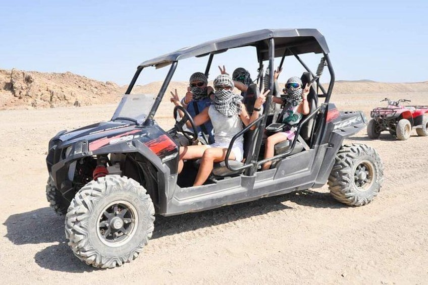 A group of people in a desert landscape, riding an off-road vehicle. 3