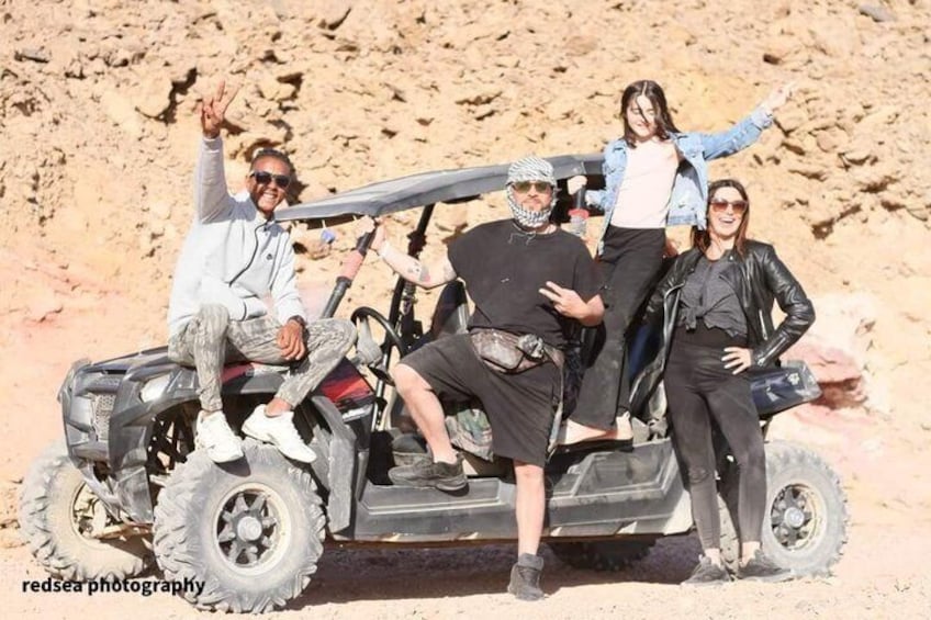 A group of people on an off-road vehicle in a desert landscape. 3
