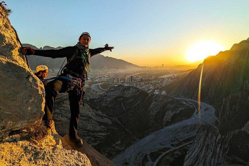 A person rappelling down a steep cliff with a cityscape in the background. 4