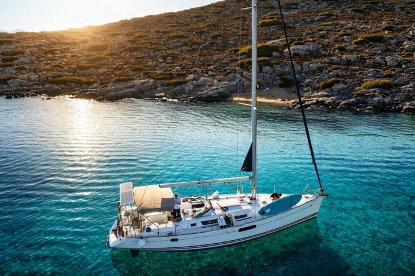 A sailboat anchored in clear turquoise waters with rocky terrain in the background. 2