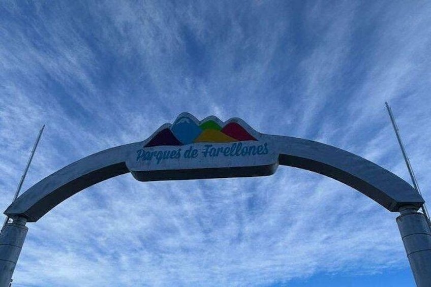 An archway with a sign that reads 'Parques de Farellones' against a blue sky with clouds. 2