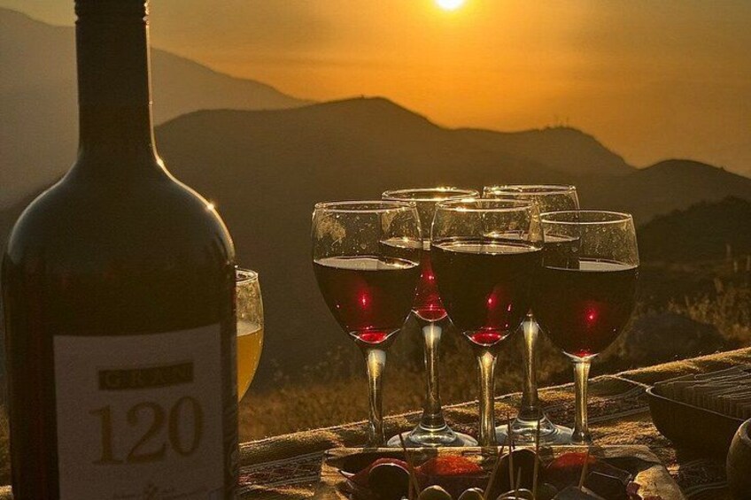 A bottle of wine, several glasses of red wine, and a scenic sunset over mountains. 5
