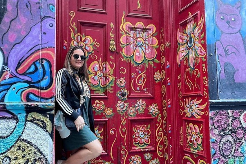 A person leaning against a brightly painted door with floral patterns. 1