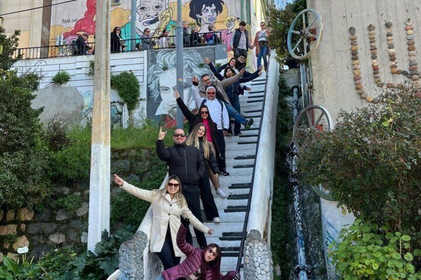 Un grupo de personas en una escalera, con un mural de fondo. 1