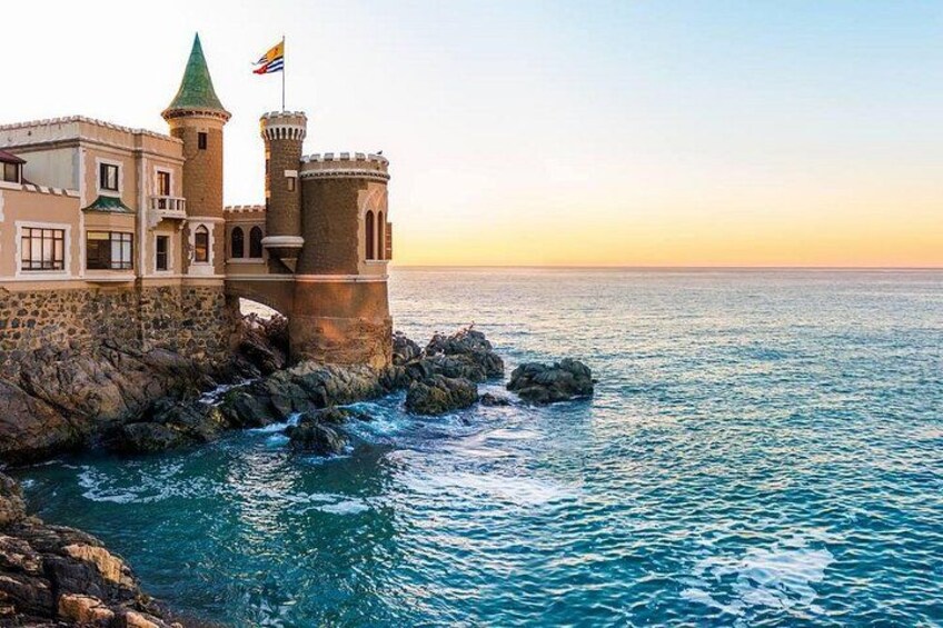 A coastal castle with a flag, surrounded by rocky terrain and the sea. 3