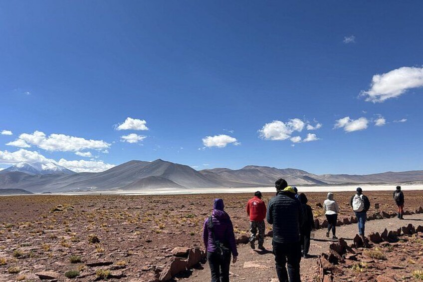 Un groupe de personnes marchant sur un terrain rocailleux, avec des montagnes en arrière-plan. 5