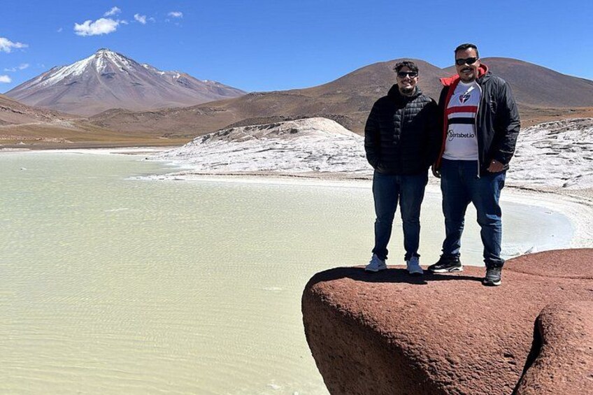 Deux personnes se tiennent debout sur un rocher, au bord d’un lac, avec une montagne en arrière-plan. 2