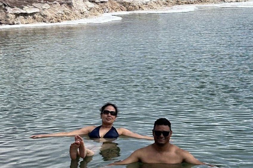 Two people in a body of water with a rocky shoreline in the background. 5