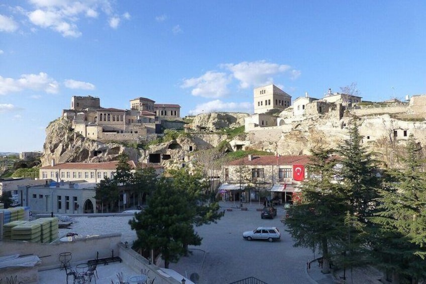 Un pueblo con edificios históricos en una colina, cielo despejado y una carretera con vehículos. 2