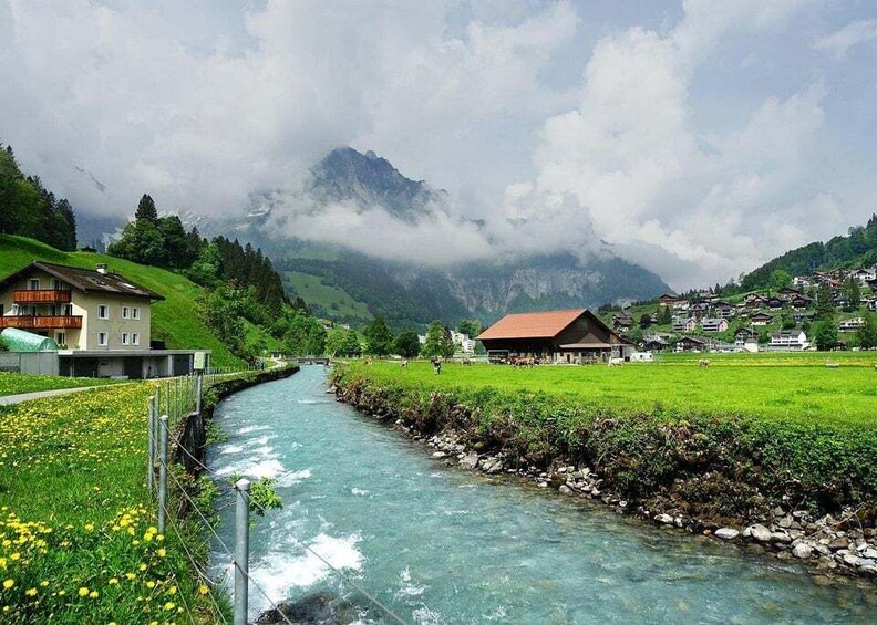 A river flowing through a valley with houses and mountains in the background. 3