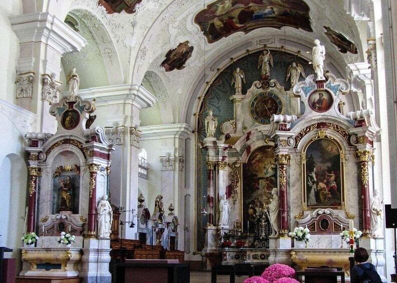 An ornate church interior with statues, altars, and a large painting. 4